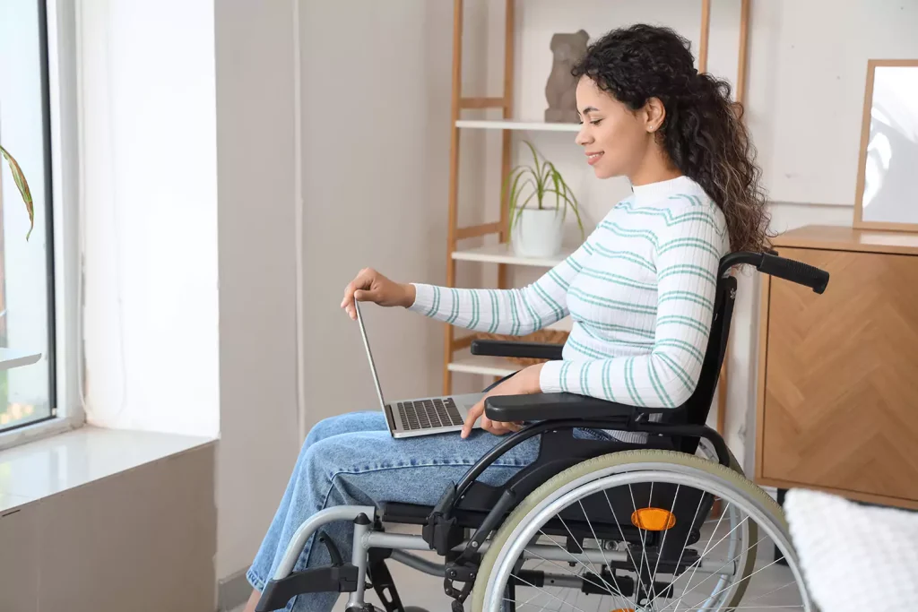 A disabled woman sitting in her wheelchair while looking at her laptop